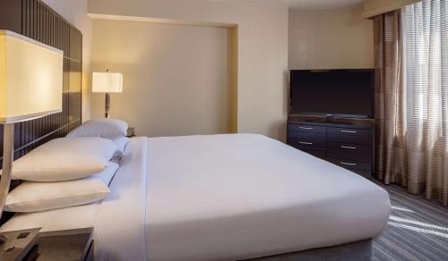 a bedroom with a large white bed and a flat screen tv at DoubleTree Suites by Hilton Minneapolis Downtown in Minneapolis