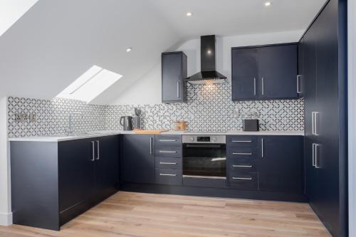 a kitchen with navy blue cabinets and a stove at Capital East Apartment in Belfast