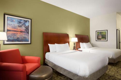 a hotel room with two beds and a chair at Hilton Garden Inn West Monroe in West Monroe