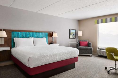 a hotel room with a bed and a chair at Hampton Inn & Suites West Haven in West Haven