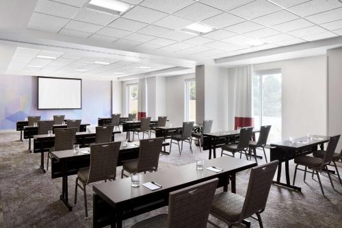 a conference room with tables and chairs and a screen at Hilton Garden Inn Denver South Park Meadows Area in Centennial