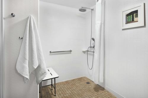 La salle de bains blanche est pourvue d'une douche et d'une serviette blanche. dans l'établissement Hampton Inn Philadelphia/King of Prussia - Valley Forge, à King of Prussia