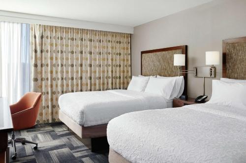 una habitación de hotel con 2 camas y una silla en Hampton Inn Philadelphia/King of Prussia - Valley Forge, en King of Prussia
