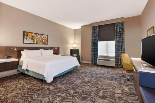 a hotel room with a bed and a flat screen tv at Hilton Garden Inn Minneapolis Maple Grove in Maple Grove