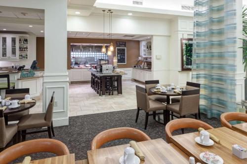 a restaurant with tables and chairs and a kitchen at Hilton Garden Inn Savannah Airport in Savannah