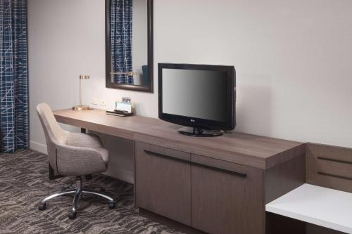 a room with a desk with a television and a chair at Hilton Garden Inn Savannah Airport in Savannah