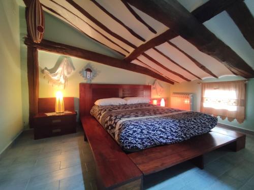 a bedroom with a large bed in a room with beams at La Aldea Encantada in Quintanilla del Monte