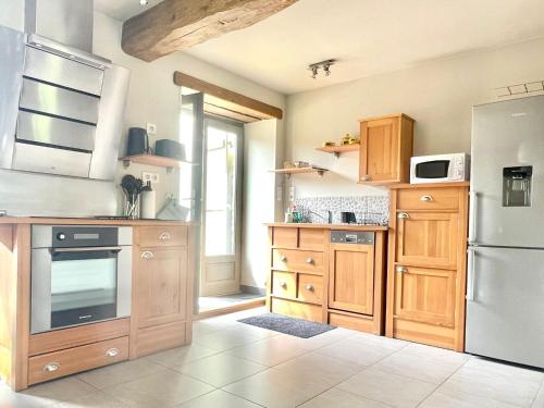 een keuken met houten kasten en een witte koelkast bij Gîte de la petite charriere in Santenay
