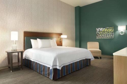Home2 Suites By Hilton Mt Pleasant Charleston في تشارلستون: غرفة نوم بسرير كبير وكرسي