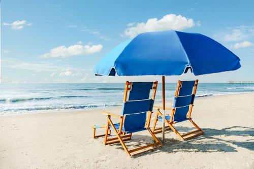 two chairs and an umbrella on the beach at Homewood Suites by Hilton Myrtle Beach Oceanfront in Myrtle Beach