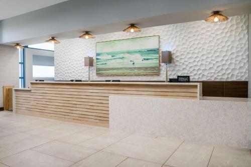 a lobby with a reception desk with a painting on the wall at Homewood Suites by Hilton Myrtle Beach Oceanfront in Myrtle Beach
