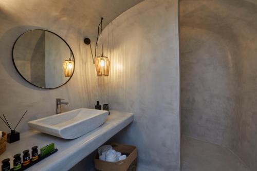 a bathroom with a sink and a mirror at Arxegono Cave Houses Santorini in Pirgos