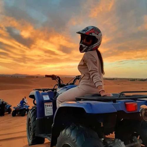 a woman sitting on the back of a atv in the desert at Magic Carpet camp in Merzouga