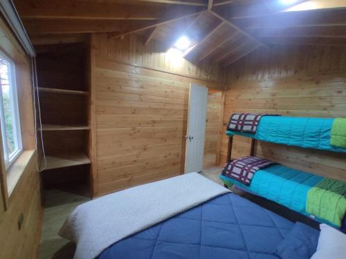 a small room with two beds in a cabin at Cabaña Los Alerces in Licán Ray