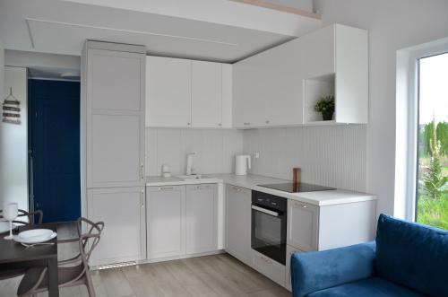 a kitchen with white cabinets and a blue couch at Morze Wyspa in Gdańsk