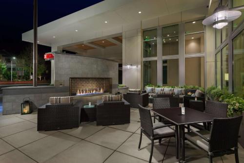 a restaurant with a fireplace and tables and chairs at Hilton Garden Inn Palo Alto in Palo Alto
