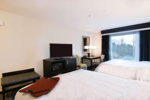 a hotel room with two beds and a flat screen tv at Hampton Inn & Suites Bellevue Downtown/Seattle in Bellevue