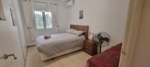 Schlafzimmer mit einem Bett, einem Ventilator und einem Fenster in der Unterkunft Villamartin Villa Oasis in Alicante