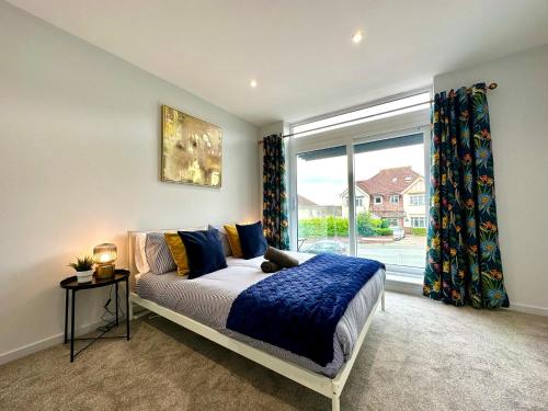 Un dormitorio con una cama y una ventana grande. en Stunning Brand New House - Sleeps 6 - Free Parking - Great Location - Fast WiFi - Smart TV - Close to Poole & Bournemouth & Sandbanks, en Poole