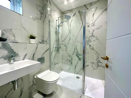Un baño con ducha, inodoro y lavabo. en Stunning Brand New House - Sleeps 6 - Free Parking - Great Location - Fast WiFi - Smart TV - Close to Poole & Bournemouth & Sandbanks, en Poole