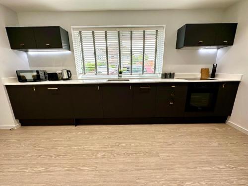 a kitchen with black cabinets and a sink and a window at Stunning Brand New House - Sleeps 6 - Free Parking - Great Location - Fast WiFi - Smart TV - Close to Poole & Bournemouth & Sandbanks in Poole