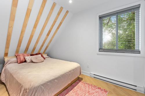 Schlafzimmer mit einem Bett und einem Fenster in der Unterkunft Le Karina - Vieux-Terrebonne in Terrebonne