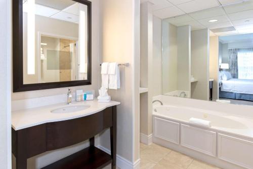 a bathroom with a sink and a tub and a mirror at Hampton Inn & Suites South Park at Phillips Place in Charlotte