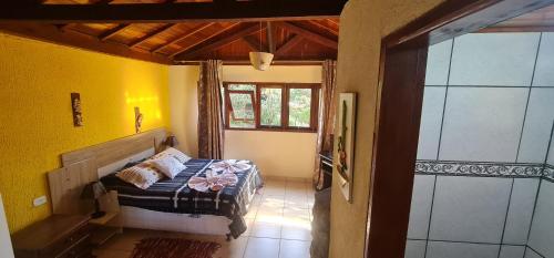 ein Schlafzimmer mit einem Bett in einem Zimmer mit gelben Wänden in der Unterkunft Pousada VISTA LINDA in São Bento do Sapucaí
