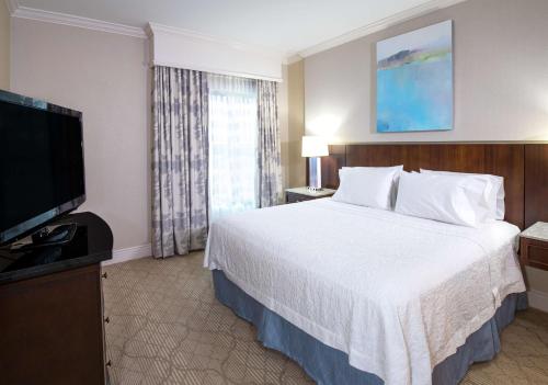 a hotel room with a bed and a flat screen tv at Hampton Inn & Suites South Park at Phillips Place in Charlotte