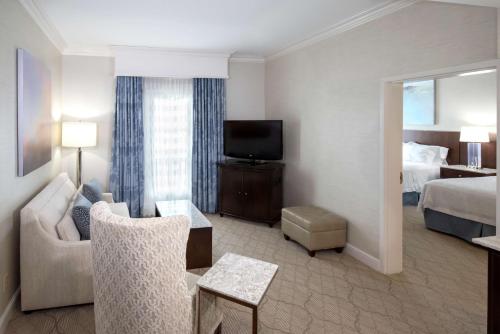 a hotel room with a couch and a bed and a television at Hampton Inn & Suites South Park at Phillips Place in Charlotte