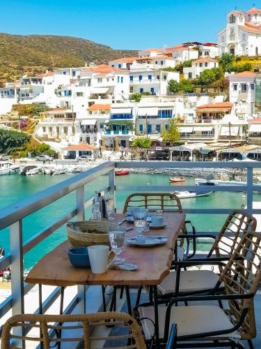 a table on a balcony with a view of a harbor at Isalos Stay Andros in Batsi