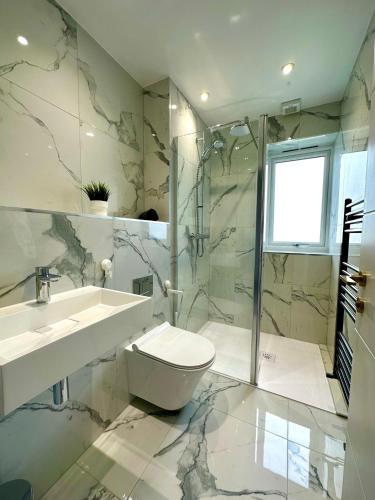 a bathroom with a toilet and a sink and a shower at Brand New 4 Bedroom House -Sleeps 9 - Free Parking - Great Location - Fast WiFi - Smart TV - Close to Poole & Bournemouth & Sandbanks in Poole
