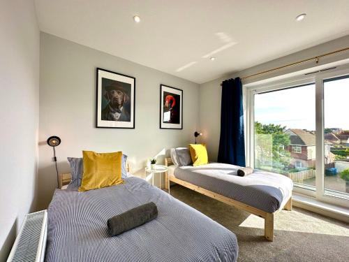 a bedroom with two beds and a large window at Brand New 4 Bedroom House -Sleeps 9 - Free Parking - Great Location - Fast WiFi - Smart TV - Close to Poole & Bournemouth & Sandbanks in Poole