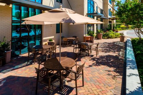 patio ze stołami, krzesłami i parasolem w obiekcie Hampton Inn & Suites National Harbor/Alexandria Area w mieście National Harbor