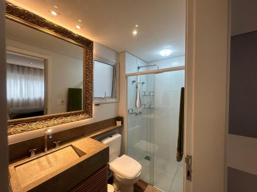 uma casa de banho com um WC, um chuveiro e um espelho. em Apartamento no Estreito em Florianópolis