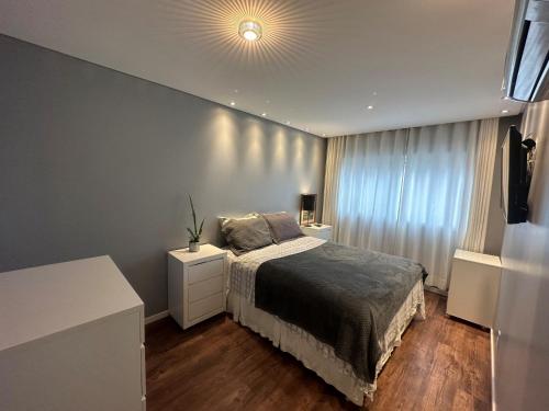 um quarto com uma cama e uma grande janela em Apartamento no Estreito em Florianópolis