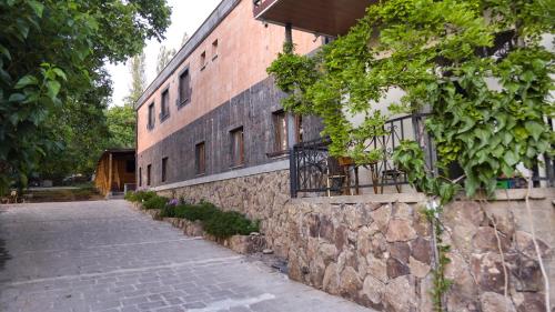 a brick building with a stone wall next to a street at Old Byurakan Gouest House in Byurakan