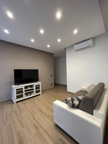 sala de estar con sofá blanco y TV de pantalla plana en Casetta Tini, en Grottaferrata