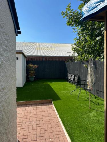 a backyard with a lawn with two chairs and a fence at 2 bedroom semi-detached house- sleeps 4 in Newport