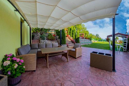 a patio with a couch and a table under an umbrella at PENSIUNEA MIHAELA-Transalpina in Novaci