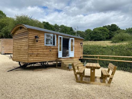 a small wooden cabin with a table and chairs at Drakes Mead Retreat - Shepherd's Hut in Axminster