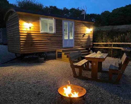 een blokhut met een tafel en een vuurplaats bij Drakes Mead Retreat - Shepherd's Hut in Axminster