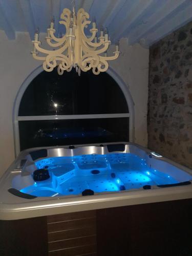 uma banheira azul na casa de banho com um lustre em Le Clos des Soyeux em Saint-Victor-sur-Rhins