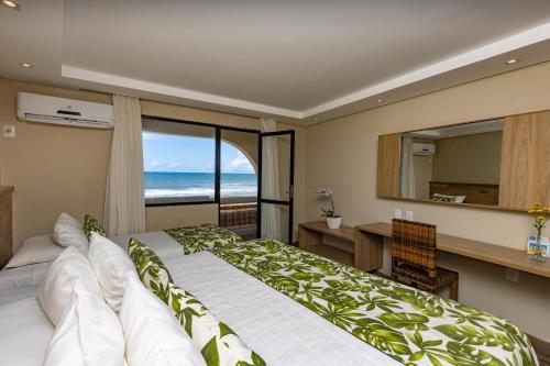 a bedroom with a bed and a desk and a window at Opaba Praia Hotel in Ilhéus