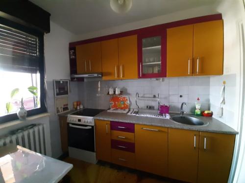 eine Küche mit Orangenschränken, einer Spüle und einem Herd in der Unterkunft Apartman Sofka in Vranje