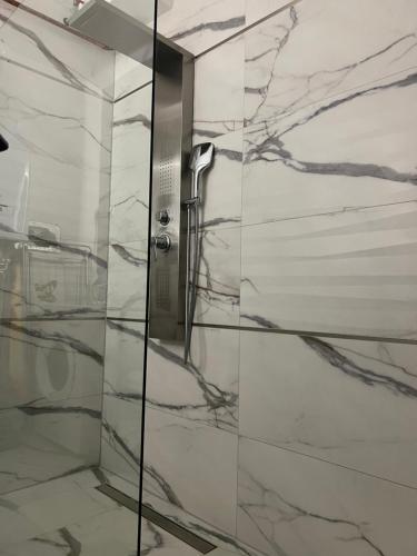 a shower with marble walls and a glass door at Oxygen Home in Nyíregyháza