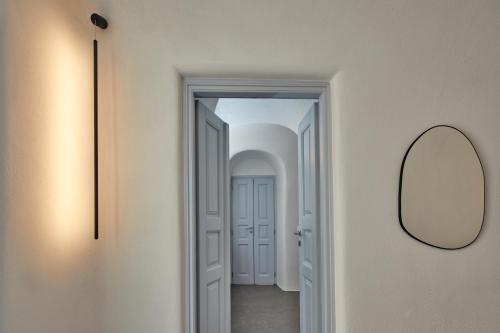 a hallway with a mirror and a hallway with a door at Arxegono Cave Houses Santorini in Pirgos