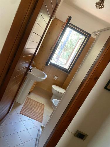a bathroom with two toilets and a window at House pinus village in Forte Village