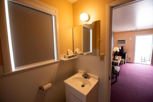 La salle de bains est pourvue d'un lavabo et d'un miroir. dans l'établissement Bells Melody Motel, à Mackinaw City