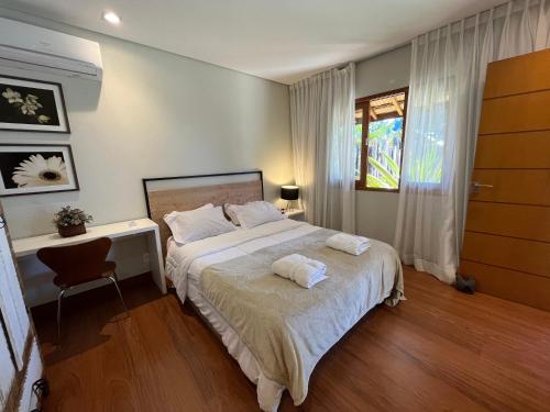 um quarto com uma cama, uma secretária e uma janela em Charmoso Chalet em Teresópolis